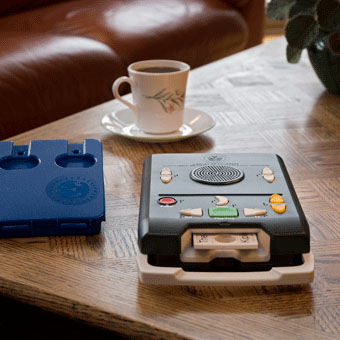a talking book machine next to a cup of tea