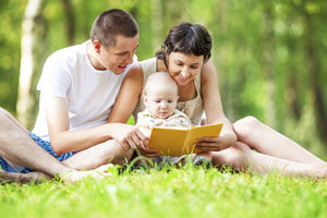 Happy family reading book in park