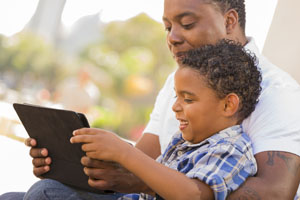 father and son reading on a portable computer