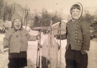 black and white photo of two kids with sled