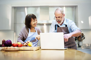 two people cooking while looking at a recipe online