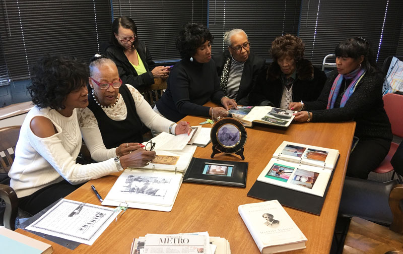 Members of the Ross family sitting around a table examining artifacts from the archive