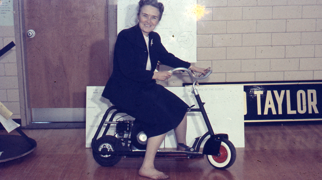 Dr. Phoebe Knipling riding a scooter at a science fair