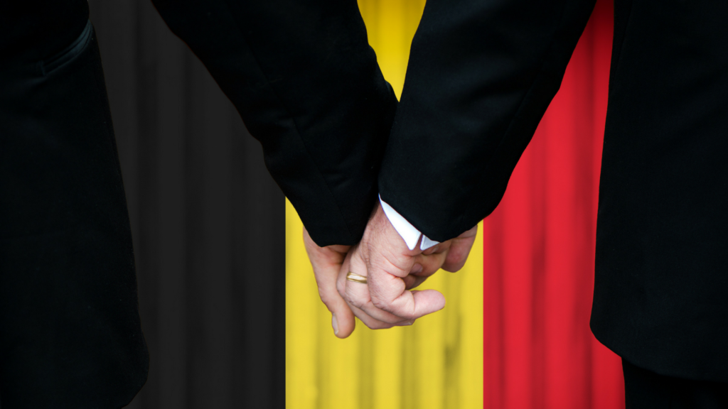 two men holding hands in front of the belgian flag