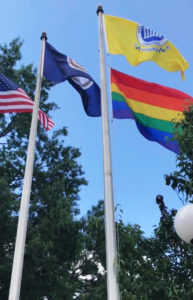 Photo of the Pride flag flying on the flagpole under the Arlington County flag at Central Library