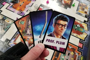 hand holding cards showing Professor Plum in the Library with the Lead Pipe in the game of Clue