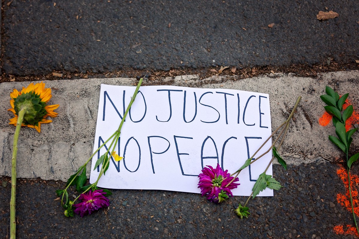 No Justice, No Peace: Sign on the ground with flowers around it