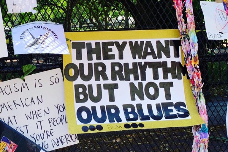 Poster reads "They Want Our Rhythm But Not our Blues"