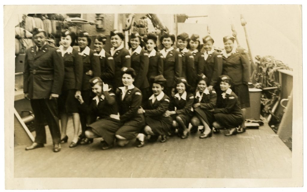 Two lines of women stand on the deck on a ship.