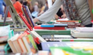 Shoppers browsing tables with used books.