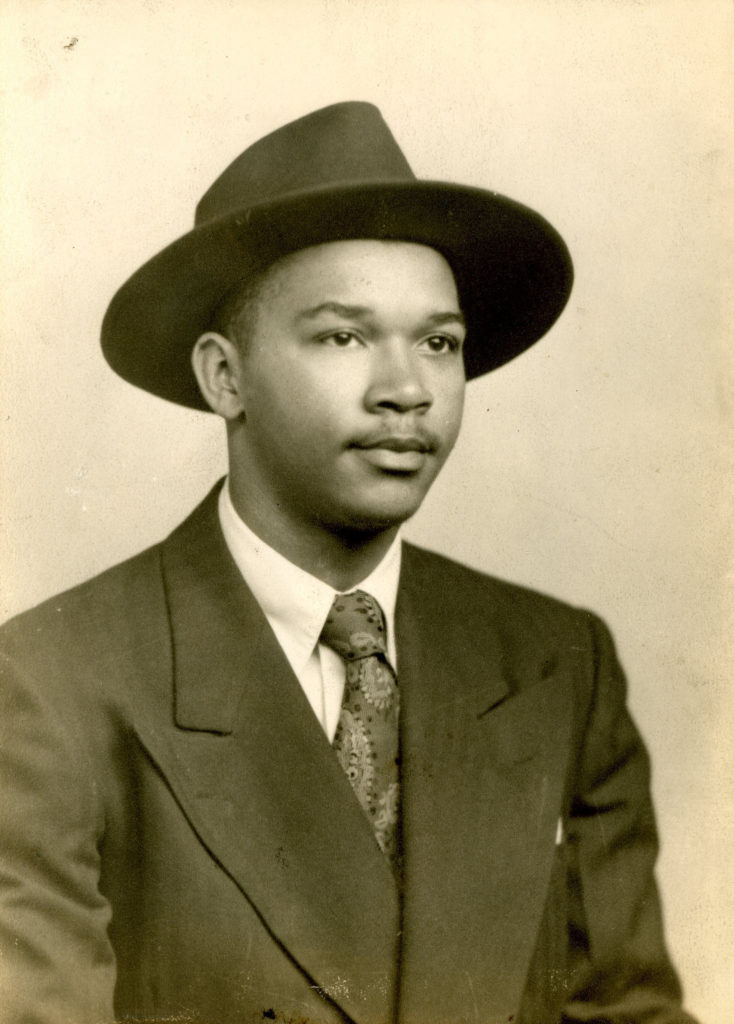 Young African American Man wearing a hat and suit.