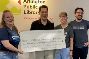 Library and FOAL representatives present a large check to Potomac Conservancy at Central Library.
