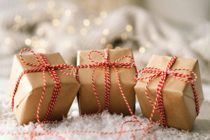 Photo of 3 brown paper parcels with holiday lights in the background.