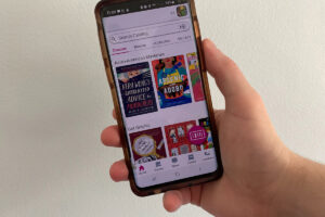 A smartphone held by a patron displays the new Library app.