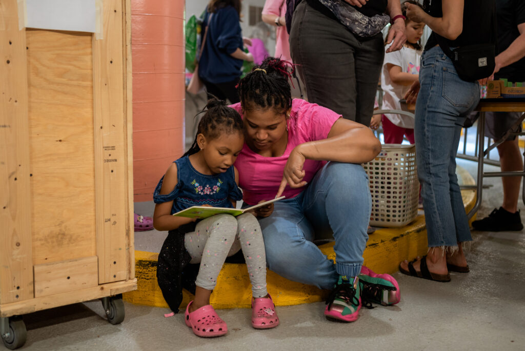 A parent and child reading at the Spring 2023 Friends of the Arlington Public Library Book Sale.