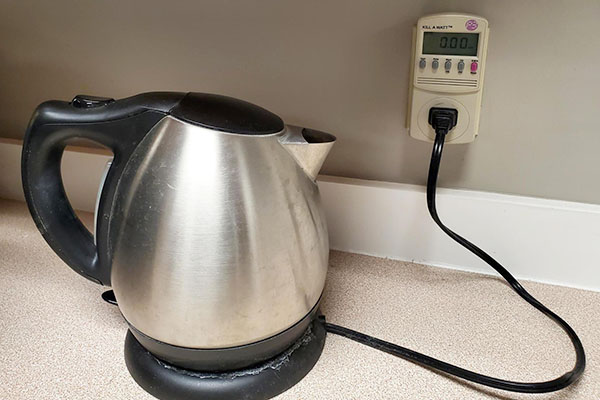 Electric kettle plugged into energy meter, which is plugged into a wall outlet.