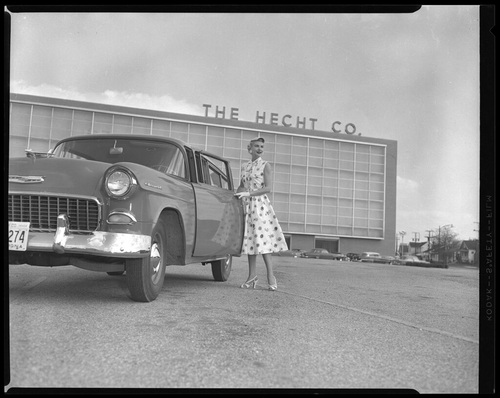 A woman poses for a photo with a car in front of Hecht's in Parkington.