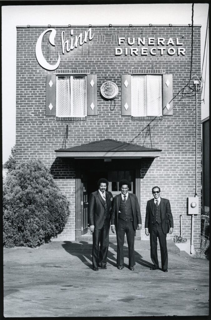 three african-american men standing outside the Chinn Funeral Service building.
