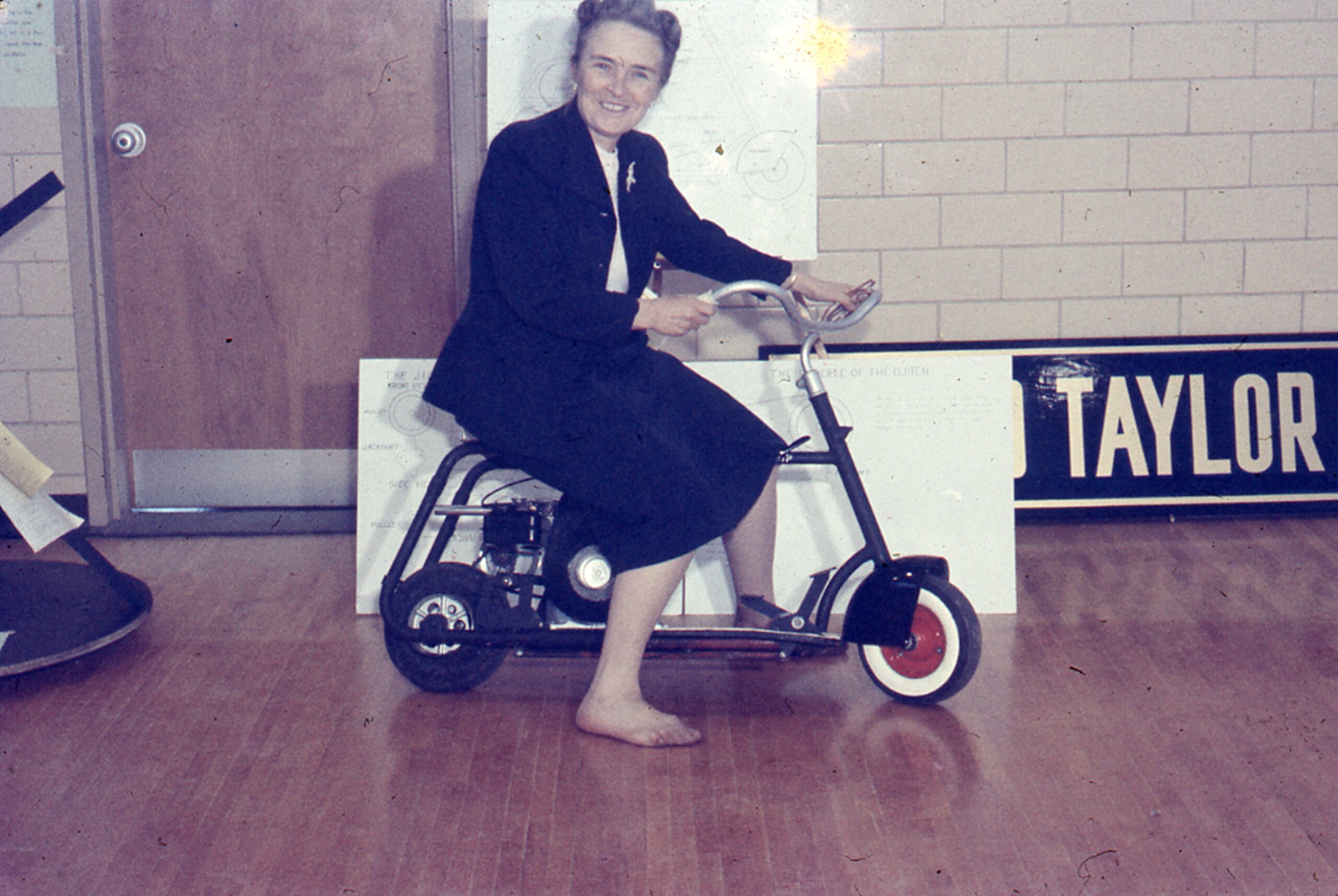 Dr. Phoebie Knipling riding a scooter at a Public School Science Fair.