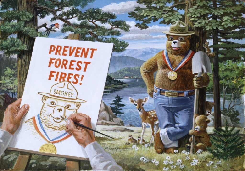 Smokey Bear in the forest with a gold medal.