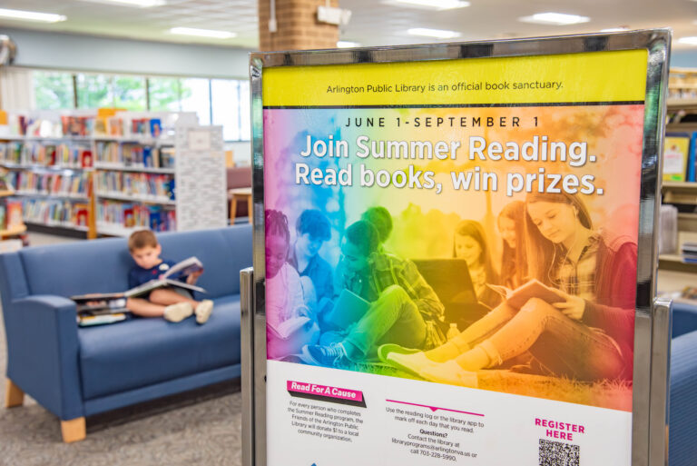 A library poster with text "Join Summer Reading. Read books, win prizes." and a child reading in the background.