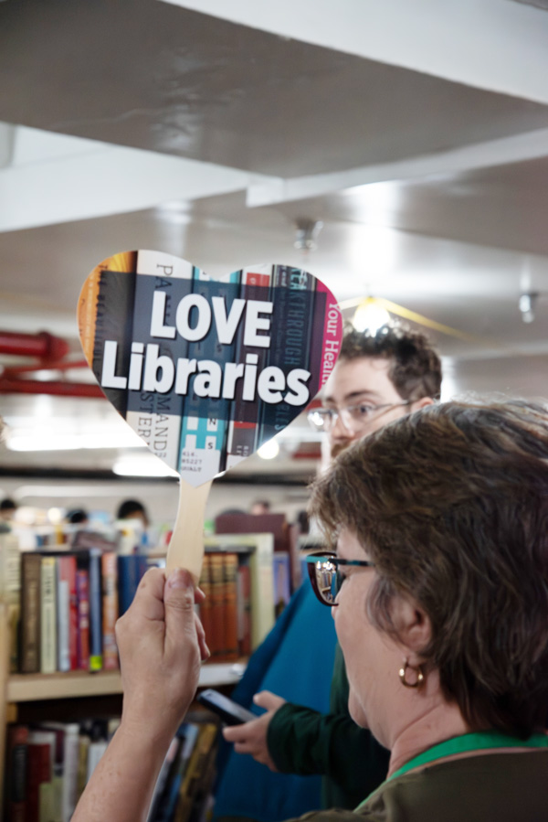 Volunteer signaling to a book sale customer to check out.