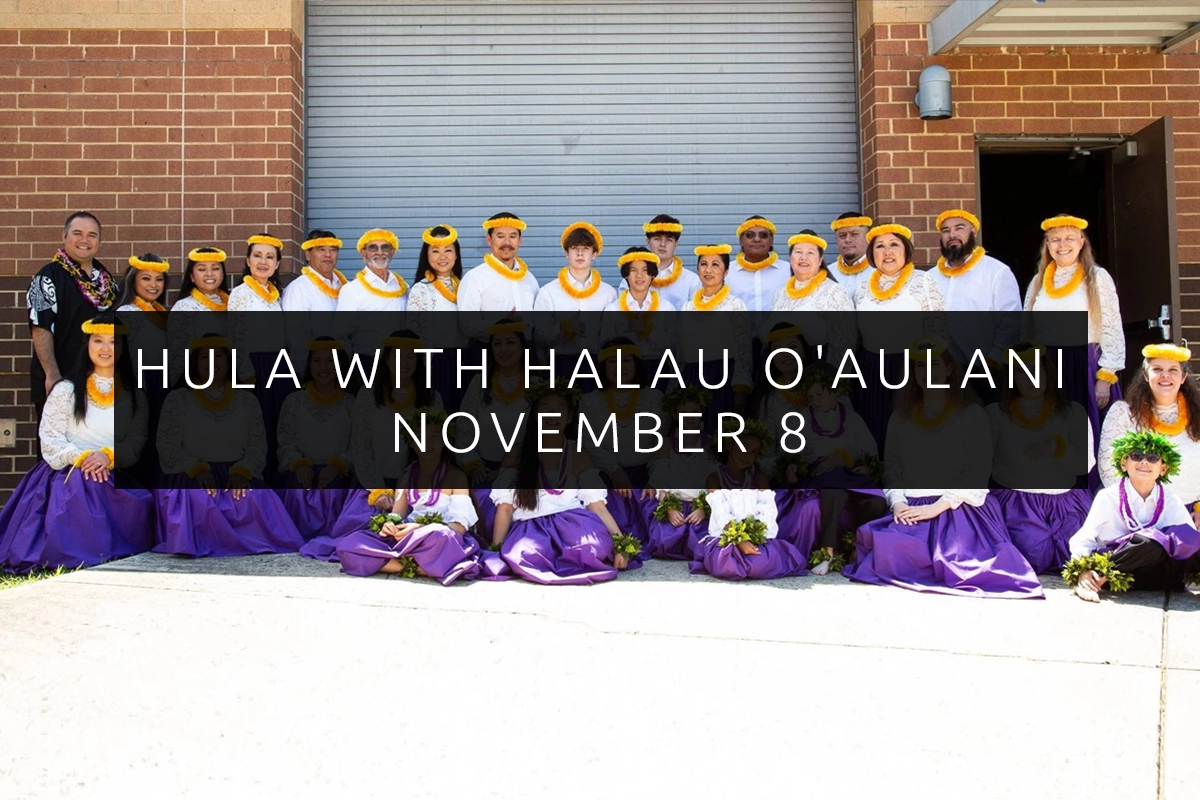 Group dressed in purple skirts and yellow leis posing outdoors in front of a brick wall and metal door, overlaid text reads Hula with Halau O’Aulani November 8.