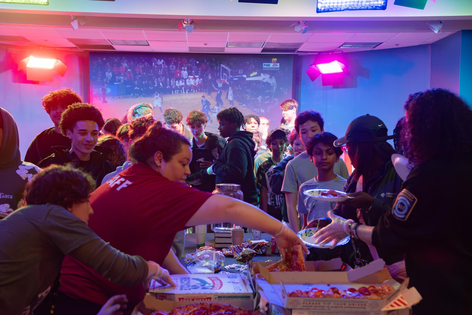 Teen Takeover pizza party. A room full of teenagers enjoying pizza and socializing.