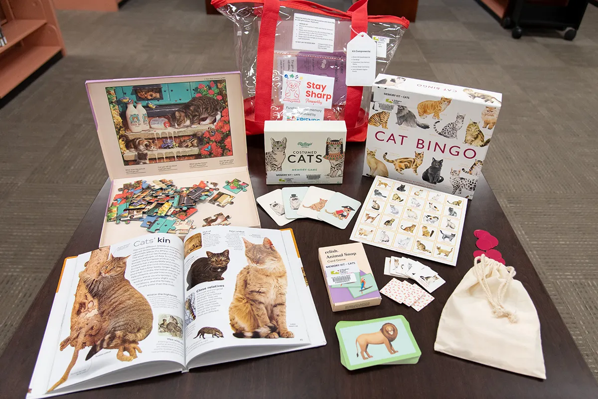 A cat-themed Memory Kit with a simple cat puzzle, book with cat facts, and bingo and card memory games featuring different kinds of cats.