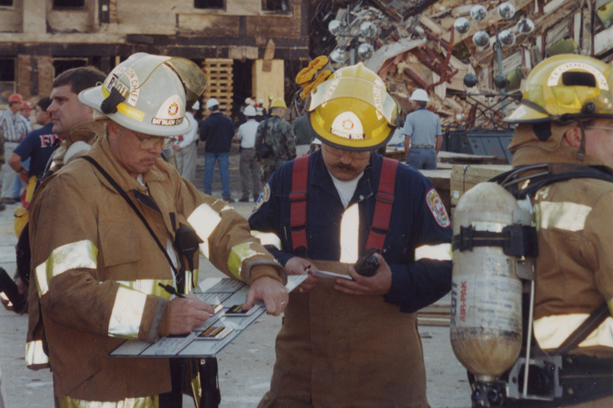 Firefighters Planning Next Steps Two firefighters draw plans to work on the impact site at the Pentagon following the 9/11 attack. Photo credit Michael Defina. Charlie Clark Center for Local History, 133-0030
