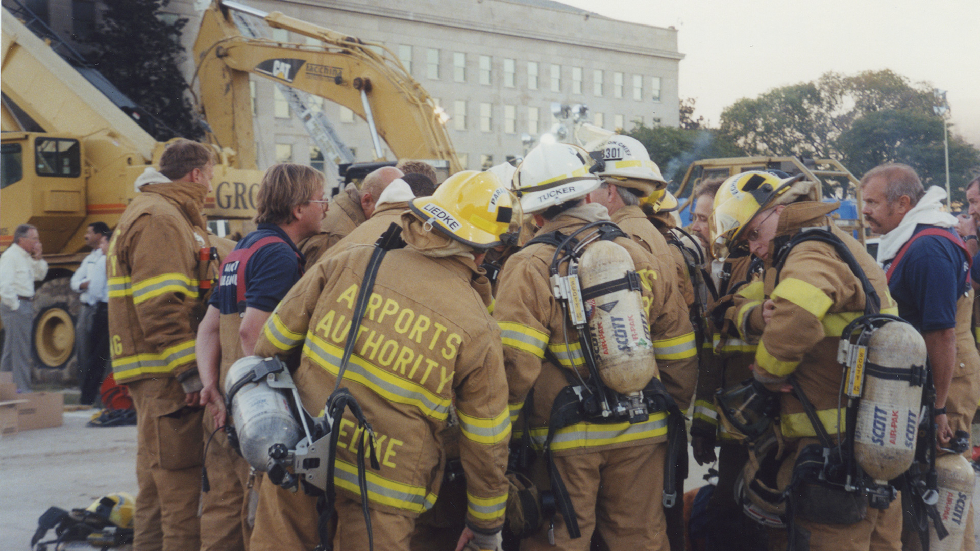 Firefighters huddling together to begin work on the morning of September 12 at the Pentagon, the day after the 9/11 attack. Photo credit Michael Defina. Charlie Clark Center for Local History, 133-01-01-01-0024