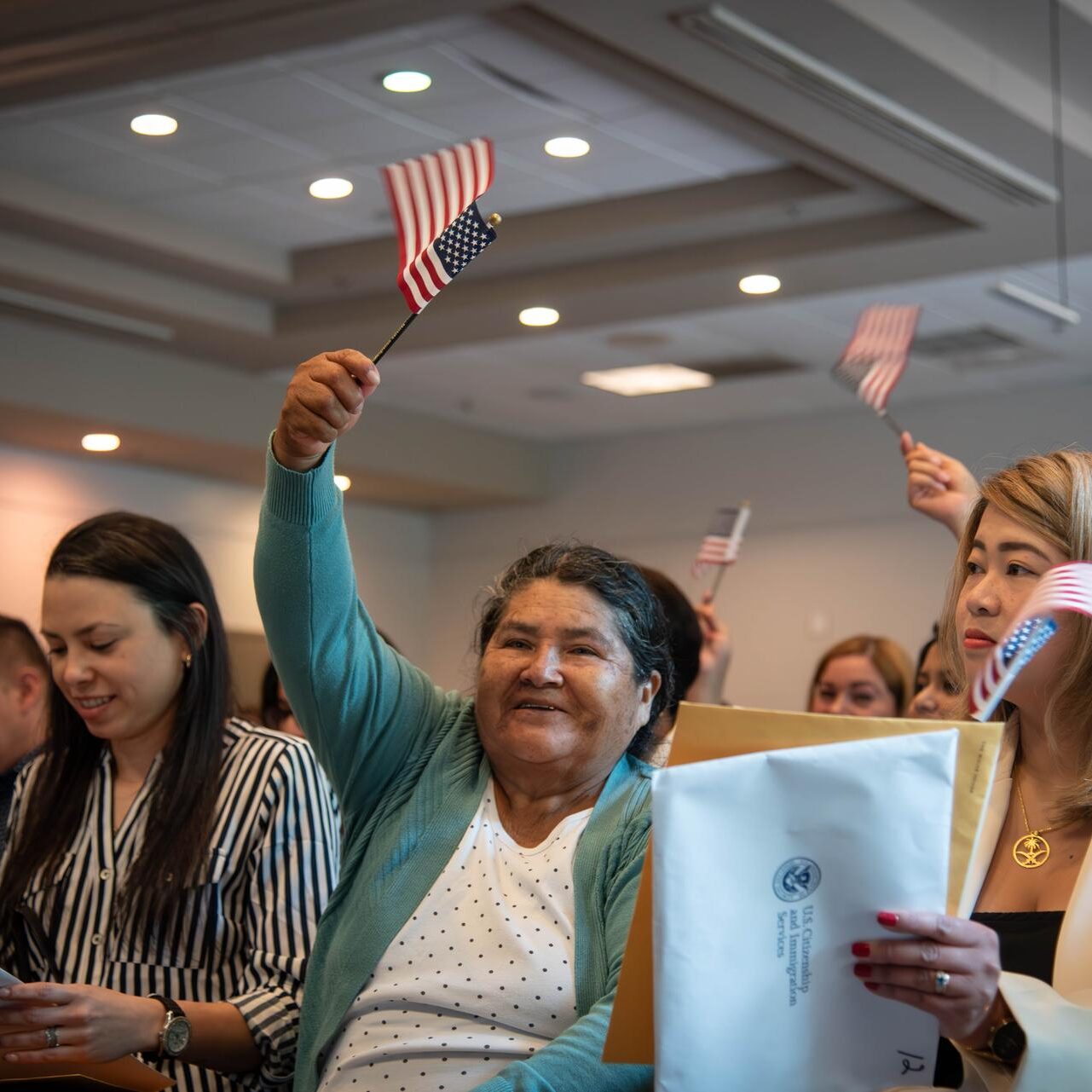 A celebratory crowd waves miniature American flags at the naturalization ceremony.
