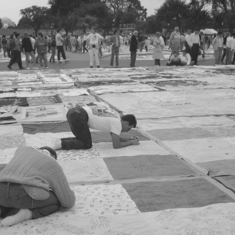 Three men writing on squares of the AIDS Quilt.
