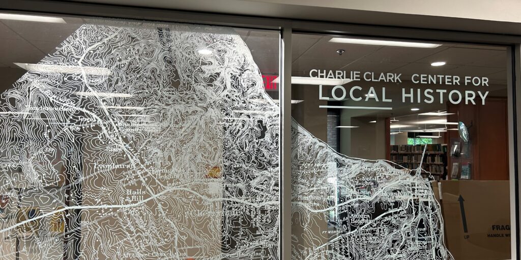 Photo of the entrance to the Center for Local History inside Central Library shows a glass door covered in a transparent map of Arlington County.