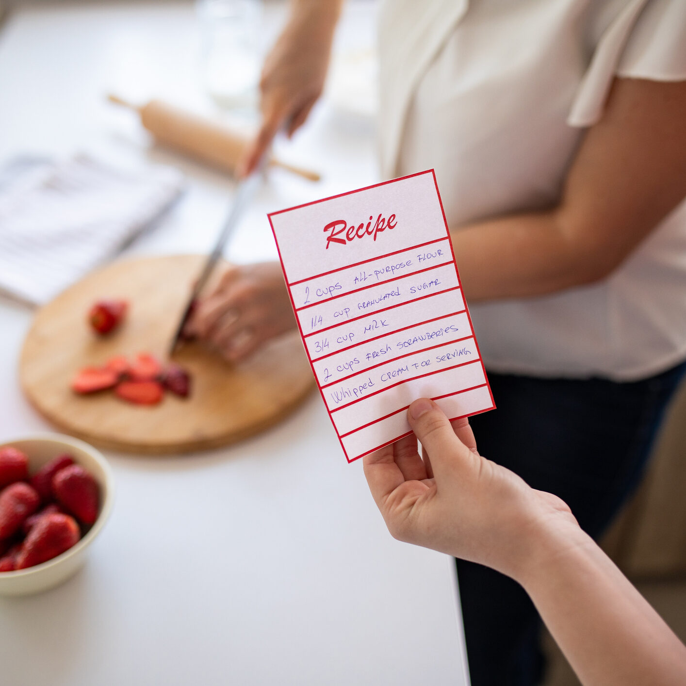 A mid adult Caucasian woman and her daughter following a recipe to bake a cake