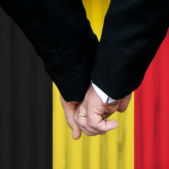 two men holding hands in front of the belgian flag