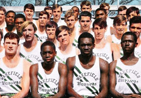 colorized photo of high school black and white boys sitting on the bleachers in track uniforms