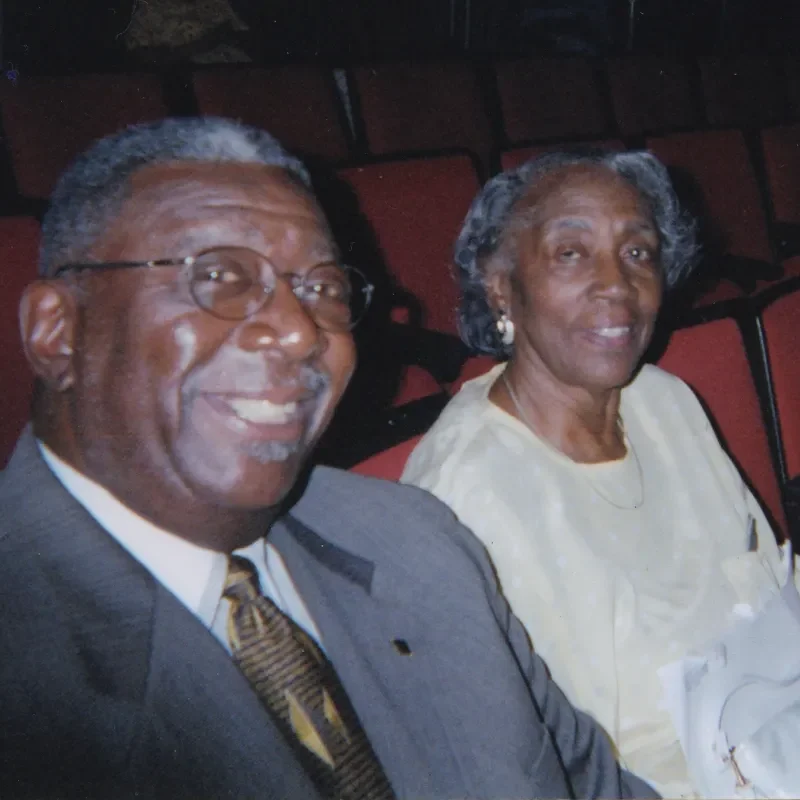 Dr. Alfred O. Taylor sits smiling next to a woman in a movie theater.