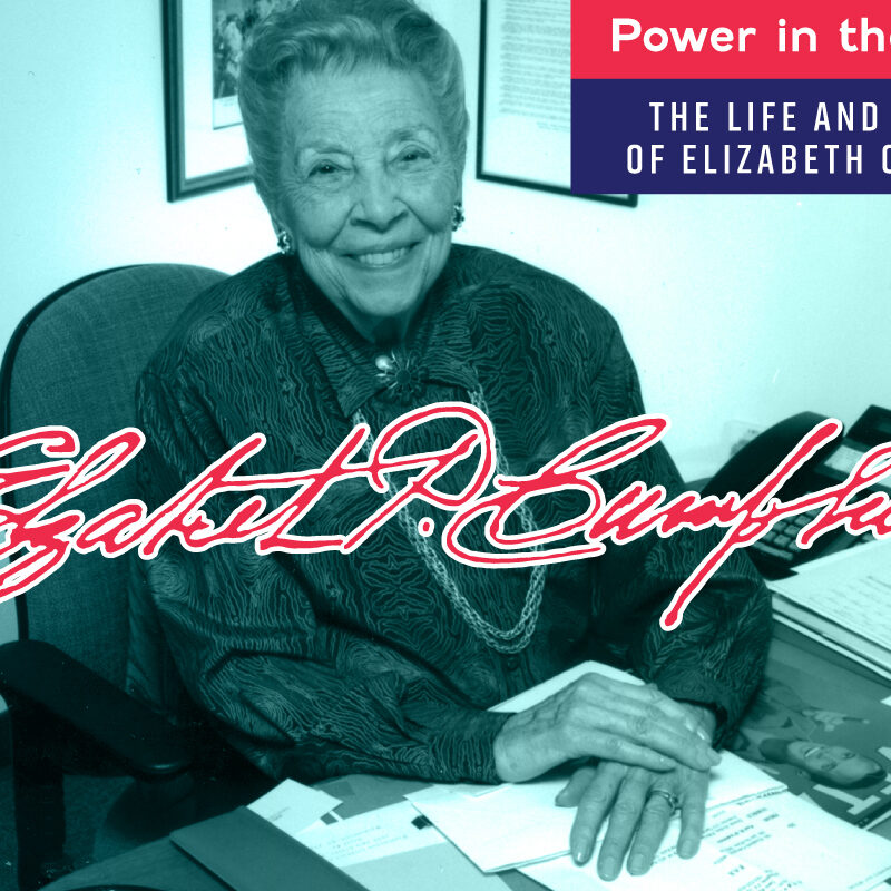 Photo of Elizabeth Campbell sitting at her desk with text logo of the exhibition "Power in the Public" and her signature. Photo credit: Chad Evans Wyatt