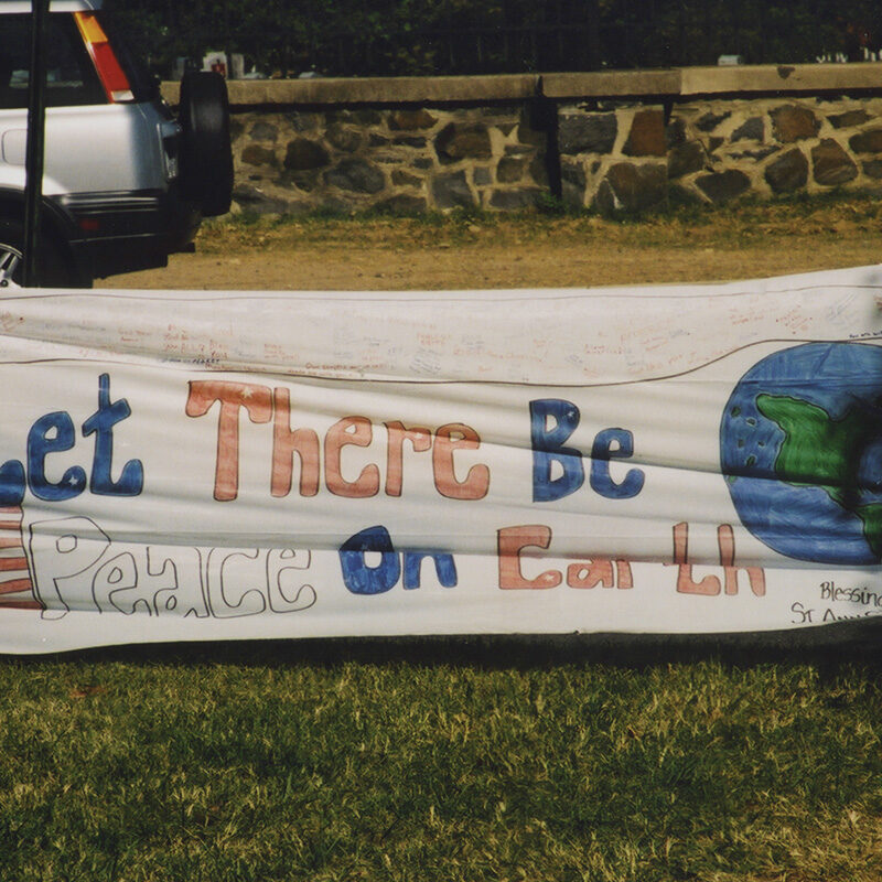 Large banner that reads, “Let there Be Peace on Earth” displayed near the Pentagon following the 9/11 terrorist attacks. Photo credit Diane Kresh. Charlie Clark Center for Local History, 133-01-02-01-130